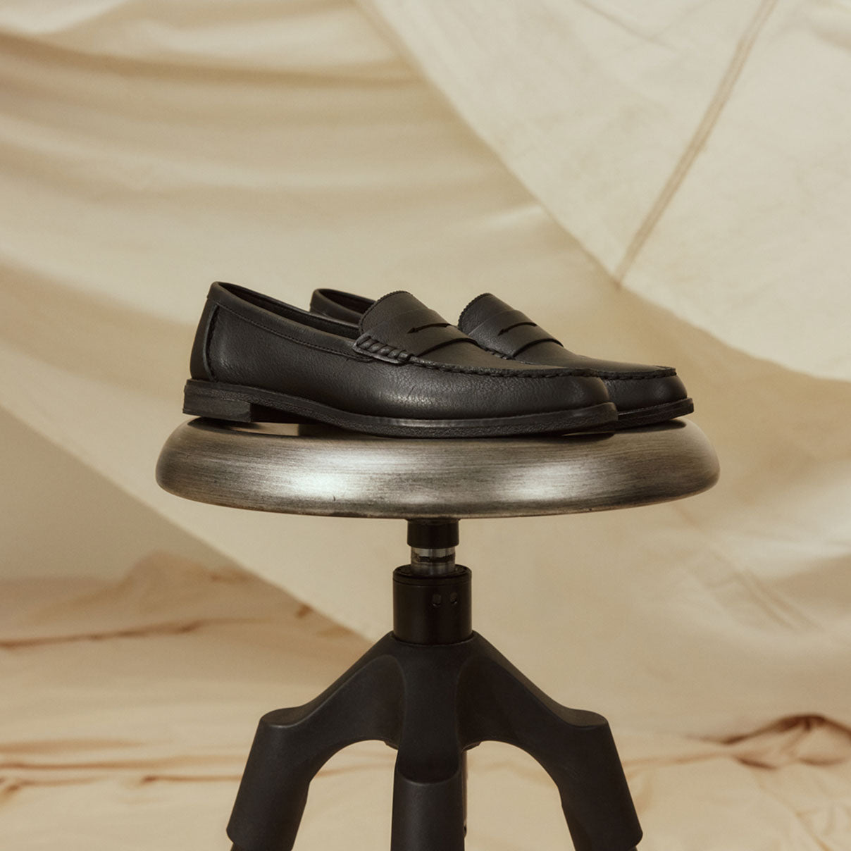 A pair of women's black loafers on a silver stool