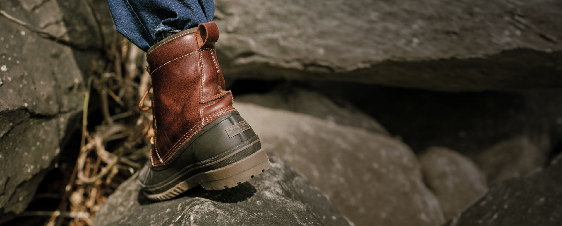 A man's burgundy boot on a rock